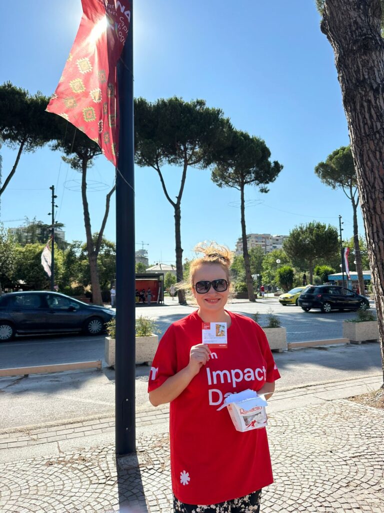 UM Tirana employee engages with passersby in the streets of Tirana, handing out cards with uplifting messages and chocolates as part of their Impact Day campaign to spread positivity and brighten people's day. 