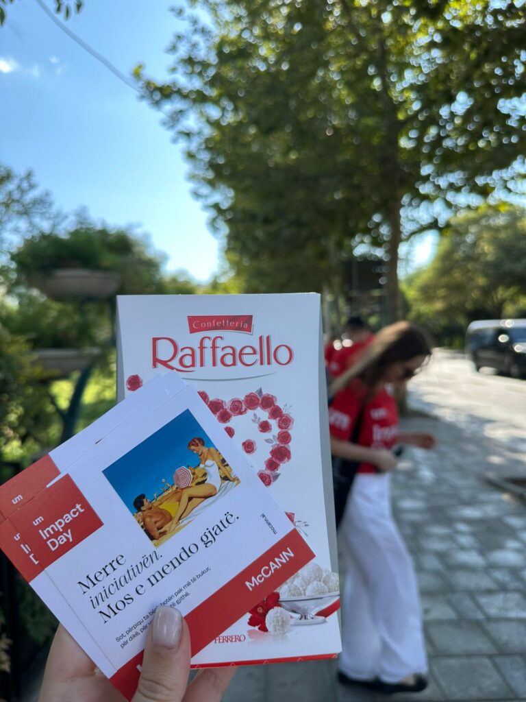 UM Tirana team members distribute inspiring message cards and chocolates to people in a busy area of the city, as part of a creative humanitarian initiative for Impact Day. 