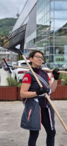 A UM Sarajevo employee is holding a rake while cleaning a park in Novo Sarajevo, actively participating in Impact Day and demonstrating teamwork and dedication to humanitarian activities. 